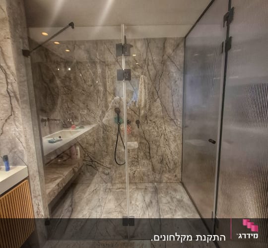 מקלחון זכוכית עם קירות שיש וברזים